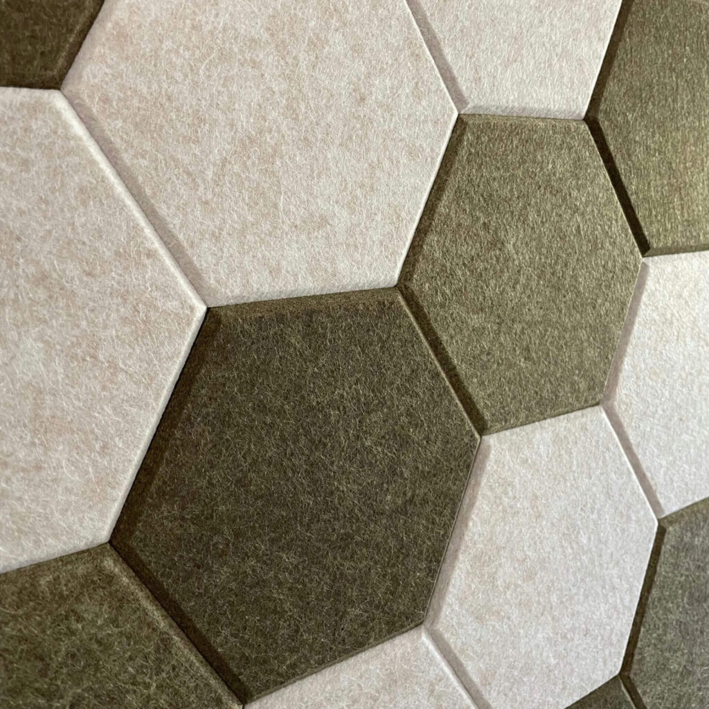 Close-up van een wand bekleed met mozaïektegels van PET-vilt, in de kleuren wit en groen.