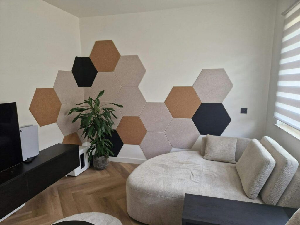 Impressie van een woonkamer met sofa, een zwevend tv-meubel en visgraat vloer. Op de wand zien we een bekleding van akoestische PET-vilt mozaïektegels, in een decoratief patroon.