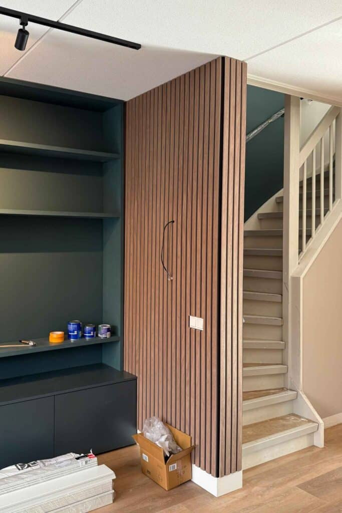 Impressie van een woonkamer die wordt ingericht, onder meer met een scheidingswand van akoestisch PET-vilt in houtlook.